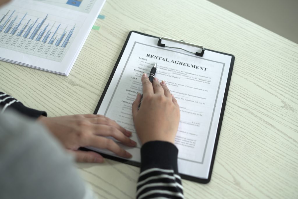 Person reviewing a residential rental lease agreement before selling a tenant-occupied property in West Michigan.